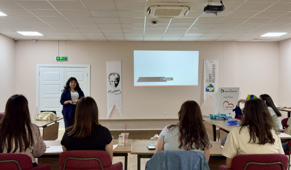 a woman standing in front of a group of people in a room